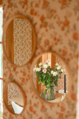a mirror with a vase of flowers on a table at Charming Vinyard House - Lake Geneva in Mont-sur-Rolle