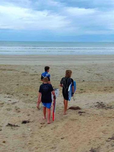 three people walking on the beach with their surfboards at The Beach House in Middleton