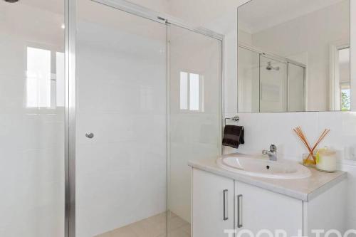 a white bathroom with a sink and a shower at The Beach House in Middleton