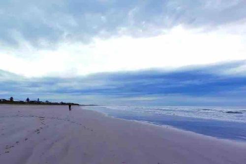 a person walking on a beach with footprints in the sand at The Beach House in Middleton