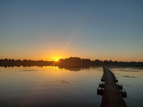 a sunset over a river with a dock at Päikesemajake 2 in Soonlepa