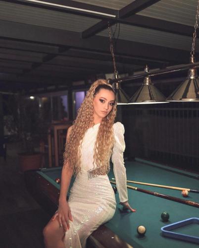 a woman in a white dress sitting on a pool table at Hotel Staccato in Prijedor