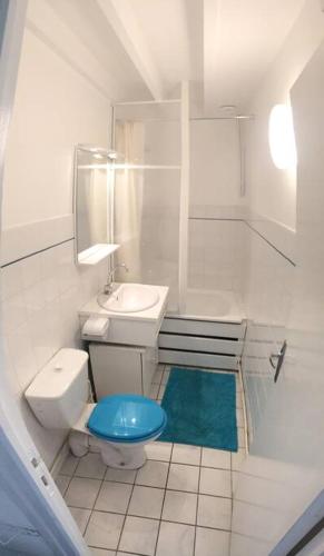 une salle de bain blanche avec des toilettes bleues et un lavabo dans l'établissement Cottage de la mer, au Crotoy