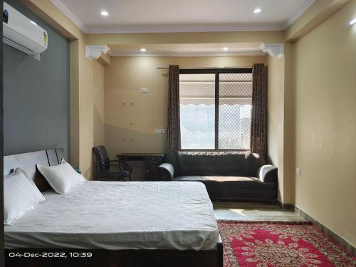 OSHO Villa Guest House في جايبور: غرفة نوم بسرير واريكة ونافذة
