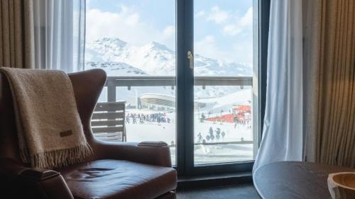 a room with a chair and a window with a view at Le Fitz Roy, a Beaumier hotel in Val Thorens