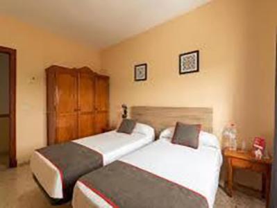 sypialnia z 2 łóżkami i drewnianą szafką w obiekcie HOSTAL-RESTAURANTE EL PAISANO w mieście Guadalema de los Quinteros