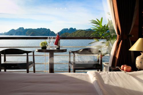a room with a bed and a table with a view of the water at V'Spirit Cruise in Ha Long