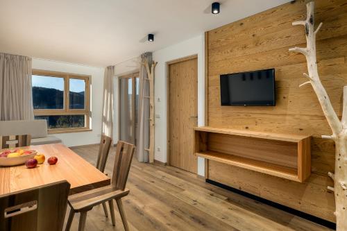 a living room with a table and a television on a wall at Neuhuberhof in Vols am Schlern