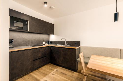 a kitchen with black cabinets and a wooden table at Neuhuberhof in Vols am Schlern