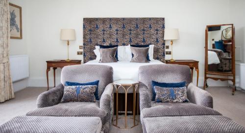 a bedroom with a large bed with two chairs at Lords Of The Manor in Upper Slaughter