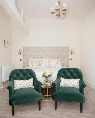 two green chairs in a bedroom with a bed at Lords Of The Manor in Upper Slaughter
