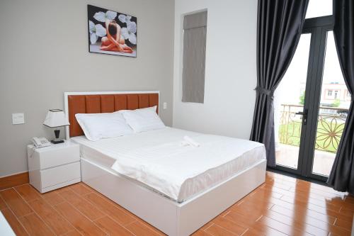a white bed in a room with a window at HAPPY HOTEL Tp Rạch Giá, Kiên Giang in Ấp Rạch Mẹo