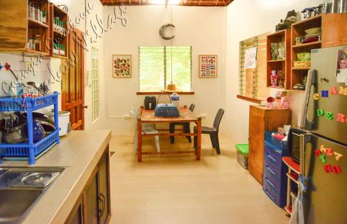 a kitchen with a table and a refrigerator at Guanyin Guesthouse at Rainbow Village in Maricaban
