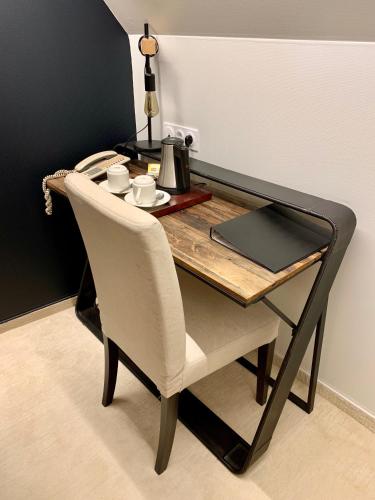 a dining room table with a chair and a table with a coffee maker at Logis Hôtel Restaurant Le Fruitier in Villedieu-les-Poëles