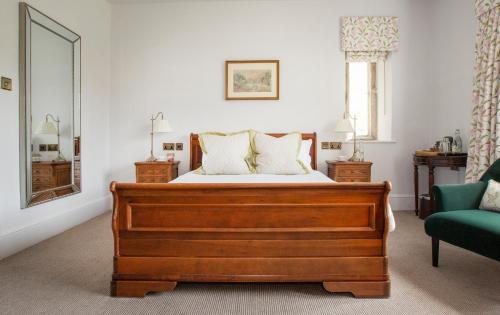 a bedroom with a bed and a green chair at Lords Of The Manor in Upper Slaughter