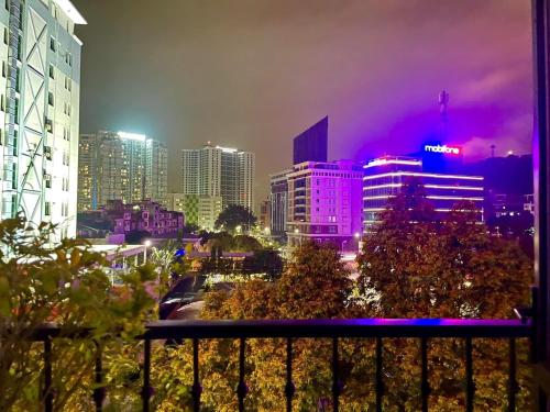 Halong Boutique Hotel في ها لونغ: أفق المدينة في الليل مع أضواء أرجوانية