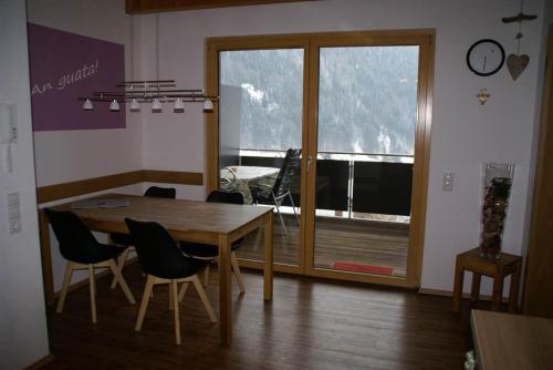 ein Esszimmer mit einem Tisch, Stühlen und einem Fenster in der Unterkunft Appartement Carola in Sankt Gallenkirch