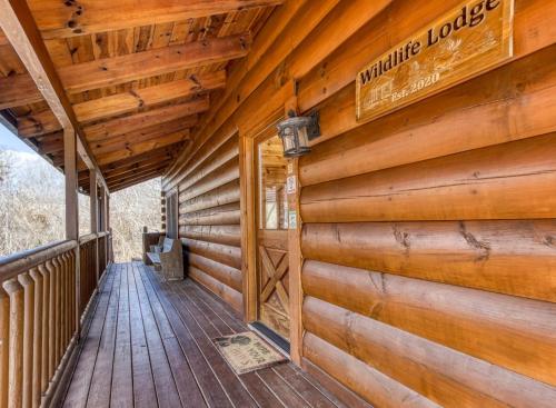 Un porche cubierto de una cabaña con una pared de madera. en The Wildlife Lodge - GREAT LOCATION! CLOSE TO TANGER OUTLETS! cabin, en Sevierville
