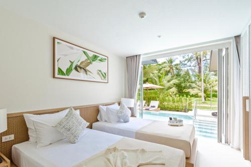 two beds in a hotel room with a large window at Twin Lotus Resort and Spa - SHA Plus - Adult Only "November - April" in Ko Lanta