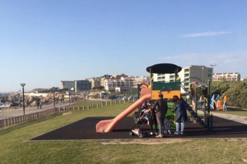 a group of people standing around a slide in a park at Rocha’s Apartment REMODELADO! Na praia com terraço in Vila Nova de Gaia