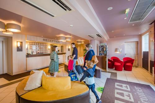 a family walking through the lobby of a store at Logis Hôtel Restaurant Le Fruitier in Villedieu-les-Poëles