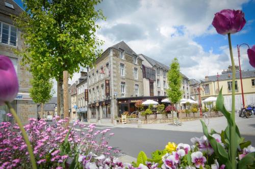 ulica miejska z kwiatami przed budynkiem w obiekcie Logis Hôtel Restaurant Le Fruitier w mieście Villedieu-les-Poëles