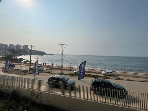 two cars parked on a road next to the beach at Hermoso y acogedor departamento a pasos del mar - Ideal Parejas, Teletrabajo in Concón
