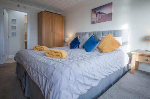 a bedroom with a large bed with blue and yellow pillows at North Beach Heights - 2 Bedroom Penthouse - Tenby in Tenby
