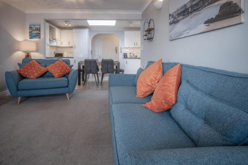 a living room with a blue couch and two orange pillows at North Beach Heights - 2 Bedroom Penthouse - Tenby in Tenby