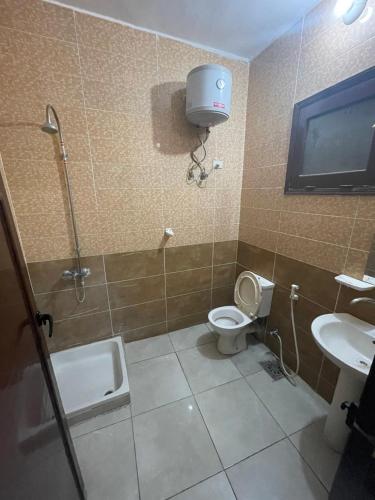 a bathroom with a toilet and a tv on the wall at Makkah Hotel in Qena