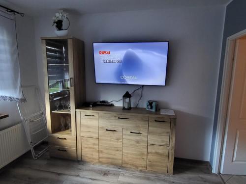 een flatscreen-tv aan de muur met een houten dressoir bij Apartament Leon in Wałbrzych