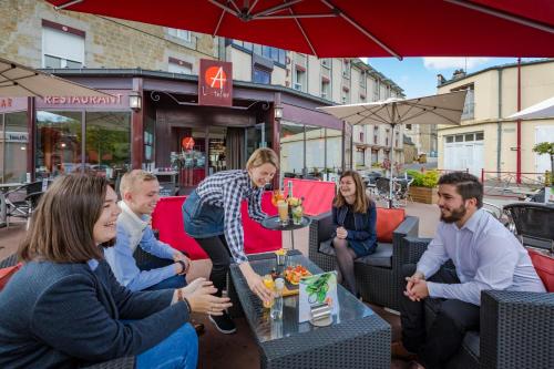 a group of people sitting around a table in a restaurant at Logis Hôtel Restaurant Le Fruitier in Villedieu-les-Poëles