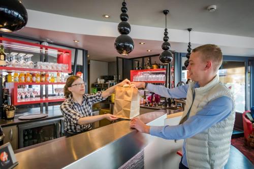 a man and a woman standing at a bar at Logis Hôtel Restaurant Le Fruitier in Villedieu-les-Poëles