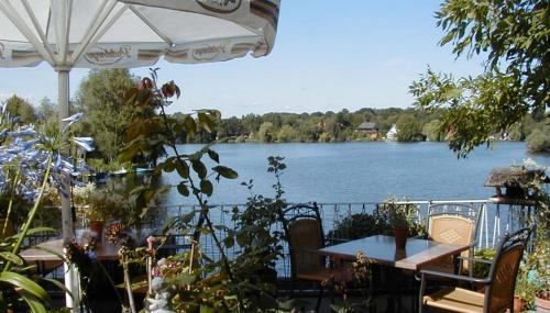 a view of a lake with tables and an umbrella at Restaurant und Hotel Zum Weissen Ross in Mölln