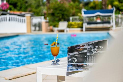 a drink sitting on a table next to a pool at Logis Hôtel & Restaurant Aux Tauzins in Montfort-en-Chalosse