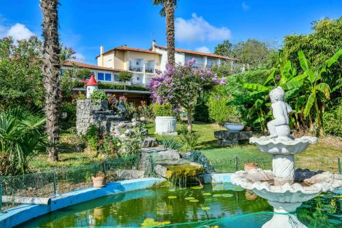 a garden with a fountain in front of a house at Logis Hôtel & Restaurant Aux Tauzins in Montfort-en-Chalosse