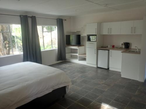 a bedroom with a bed and a kitchen with white cabinets at Garden Court in Queenstown