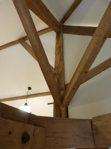 a ceiling with wooden beams and a light fixture at Logis de L'Arceau in Celles