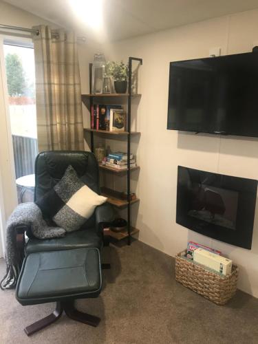 een woonkamer met een stoel en een televisie bij Ravenwood Lodge in Dollar