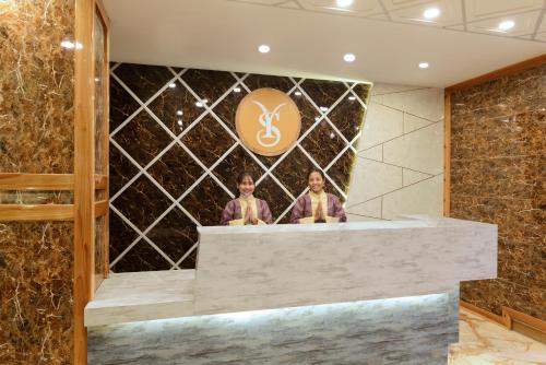 two people standing at a counter in a hotel lobby at Yashshree Sikkim Blossom 600 Meters from MG Marg in Gangtok