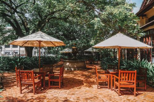 two tables and chairs with umbrellas on a patio at Settha Palace Hotel in Vientiane