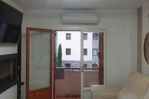 ein Wohnzimmer mit einer Tür und Blick auf ein Gebäude in der Unterkunft Acogedor apartamento en el Pirineo aragonés in Villanúa