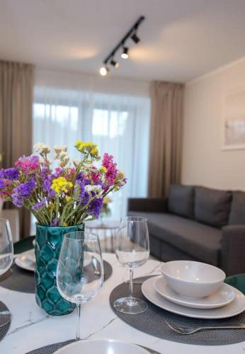 a table with a vase of flowers and wine glasses at Albatross Apartment Romantic in Ķesterciems
