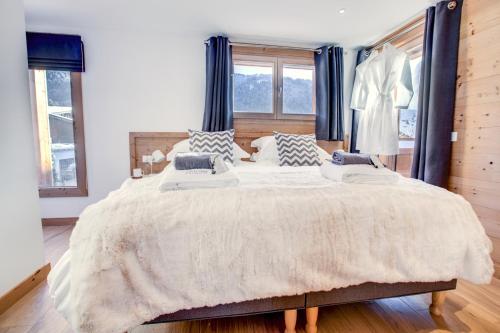 a bedroom with a large bed with blue curtains at Les Trois Bonheurs in Morzine