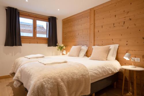 a bedroom with a large bed with a wooden wall at Les Trois Bonheurs in Morzine