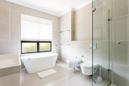 a white bathroom with a toilet and a glass shower at 8 Sovereign Sands Sea Views, Blythdale in KwaDukuza