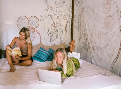 Duas raparigas deitadas numa cama com um portátil. em Mellow Hostel Sri Lanka em Ahangama