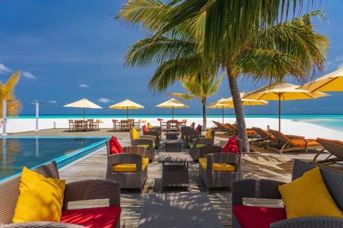un complejo con piscina, sillas y sombrillas en Dhigufaru Island Resort, en Atolón Baa