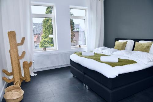 ein Schlafzimmer mit einem großen Bett und zwei Fenstern in der Unterkunft Villa Aix in Kerkrade