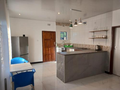 a large kitchen with a counter and a refrigerator at Kasuba Apartments in Livingstone